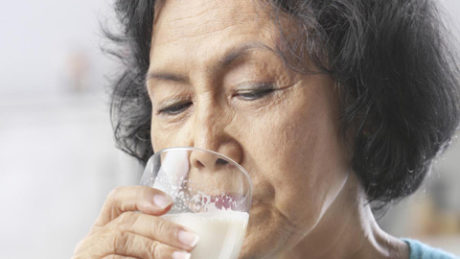 Senior Asian woman drinking milk at home
